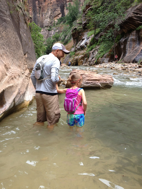 Father and daughter walk through The Narrows in Zion National Park