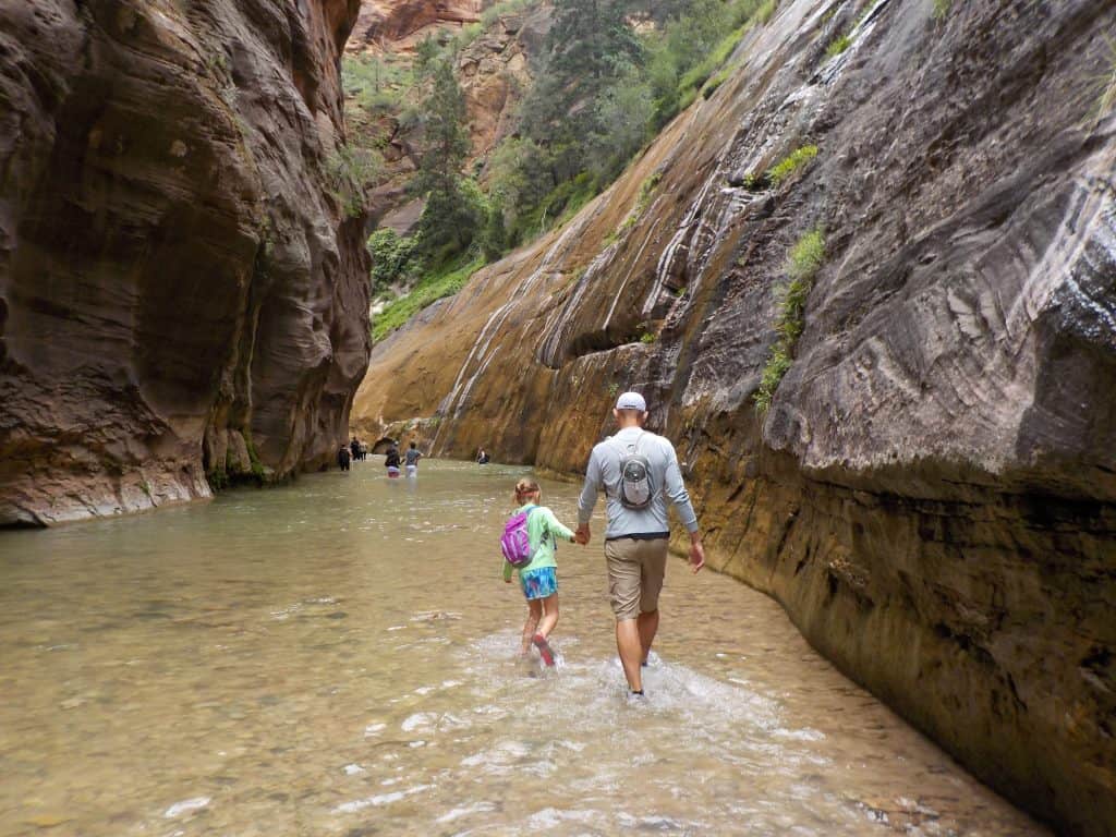 father and daughter navigate the narrows, one of the best hikes in Zion National Park