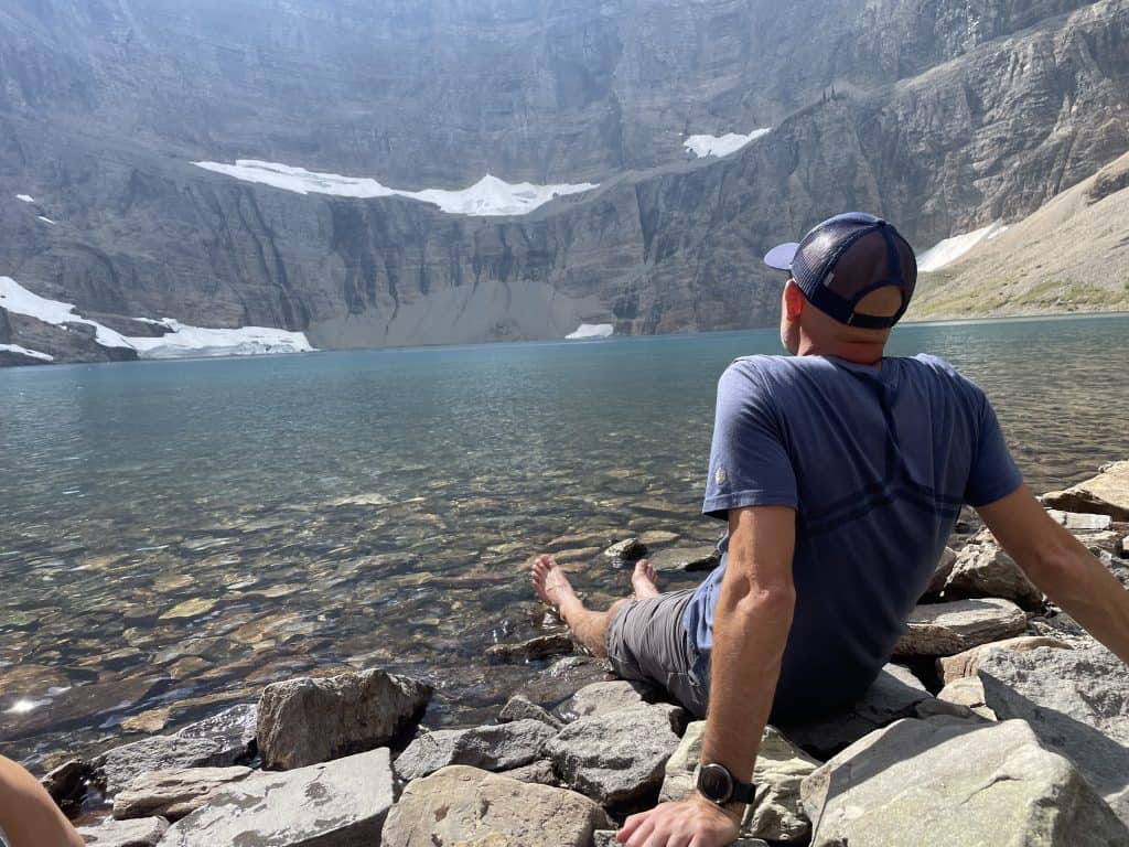 A man enjoys the ice-cold water at the shore of Iceberg Lake in Glacier National Park.